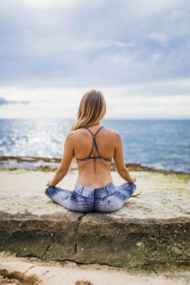 Woman practicing Bhastrika Pranayama near the sea on a rock