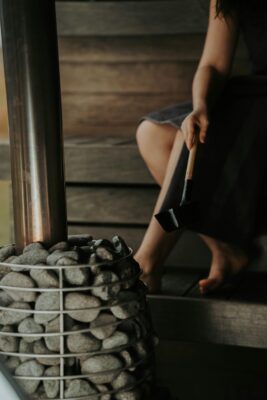 A woman setting up a heated room for a Bikram Yoga session, preparing mats and towels.