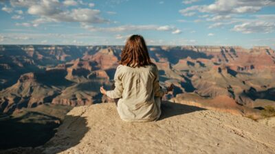 A woman meditating on a hill, practicing deep breathing for relaxation and mindfulness.