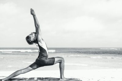 A man practicing Hatha Yoga on a beach during the day.