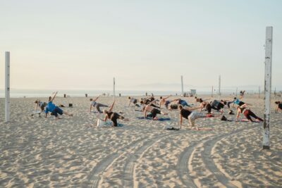 A group of people practicing yoga on a beach during International Yoga Day.