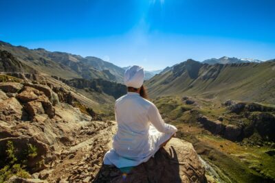 Man sitting on a rock atop a mountain practicing Kundalini Pranayama.