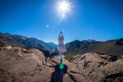 A man practicing Kundalini Yoga exercises on top of a mountain, surrounded by nature.