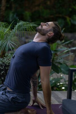 Man sitting on a yoga mat in the forest practicing lung health exercises.