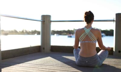 Woman practicing Nadi Shodhana Pranayama on a wooden dock with crossed legs