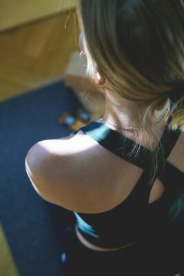 A woman sits comfortably on a yoga mat, practicing resistance breathing exercises with pursed lips, focusing on controlled exhalation.