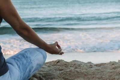 Person practicing yoga on the beach, demonstrating various types of pranayama techniques.