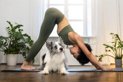 Woman practicing yoga with her puppy on a yoga mat during a Puppy Yoga session.